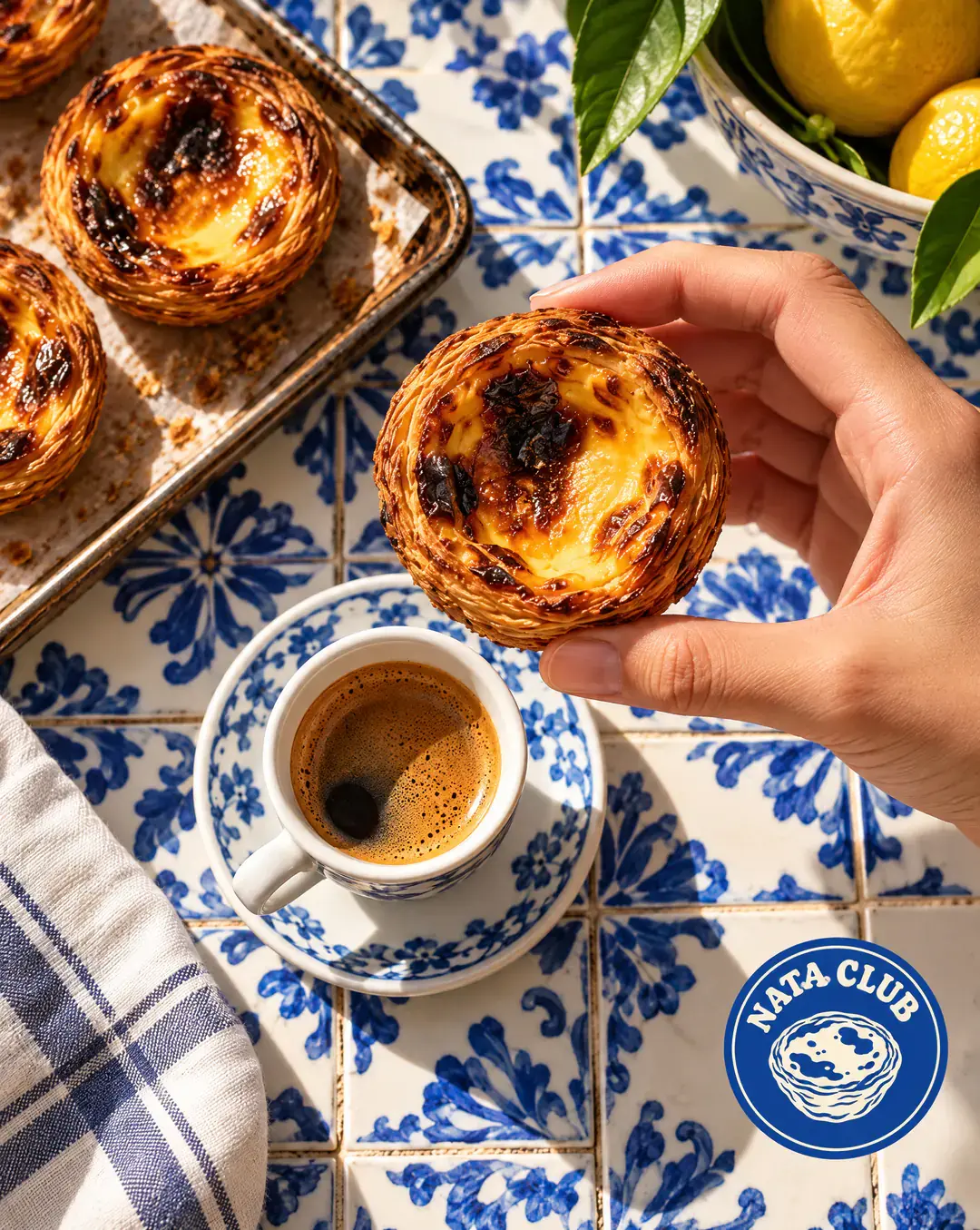 A hand holding a custard tart over an espresso on blue tiles, with the Nata Club logo in the corner